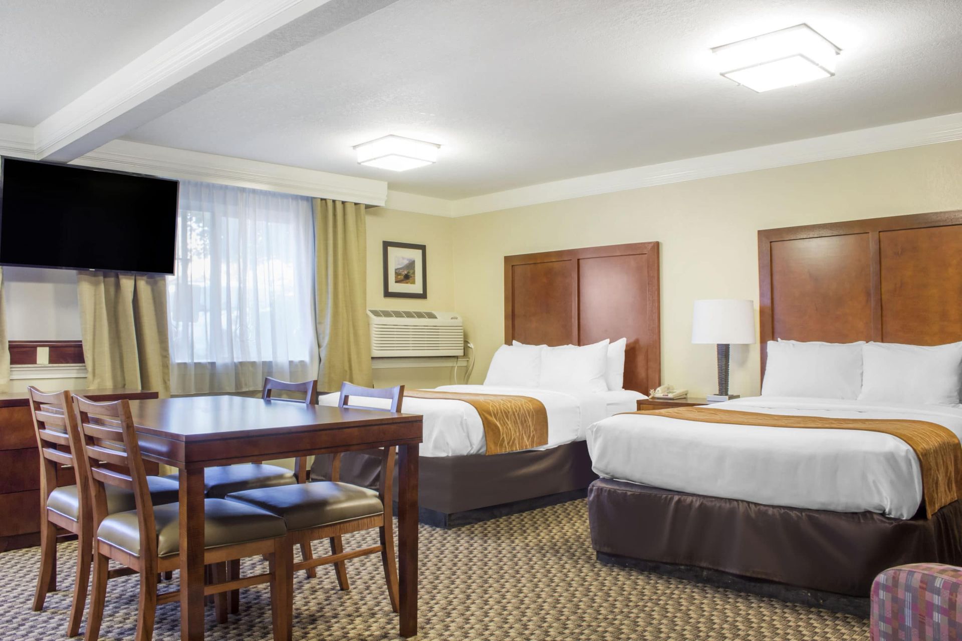 A hotel room with two beds , a table and chairs.