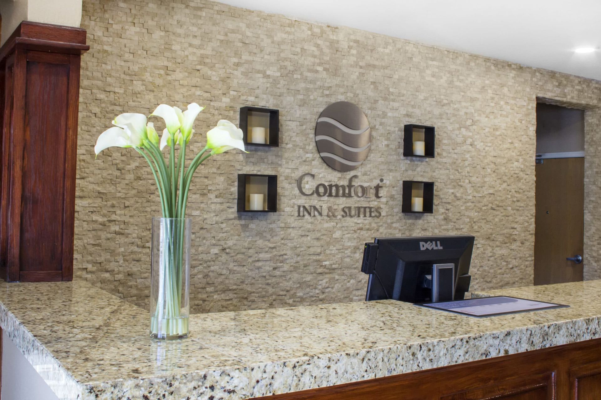 The front desk of a hotel with a vase of flowers on it.