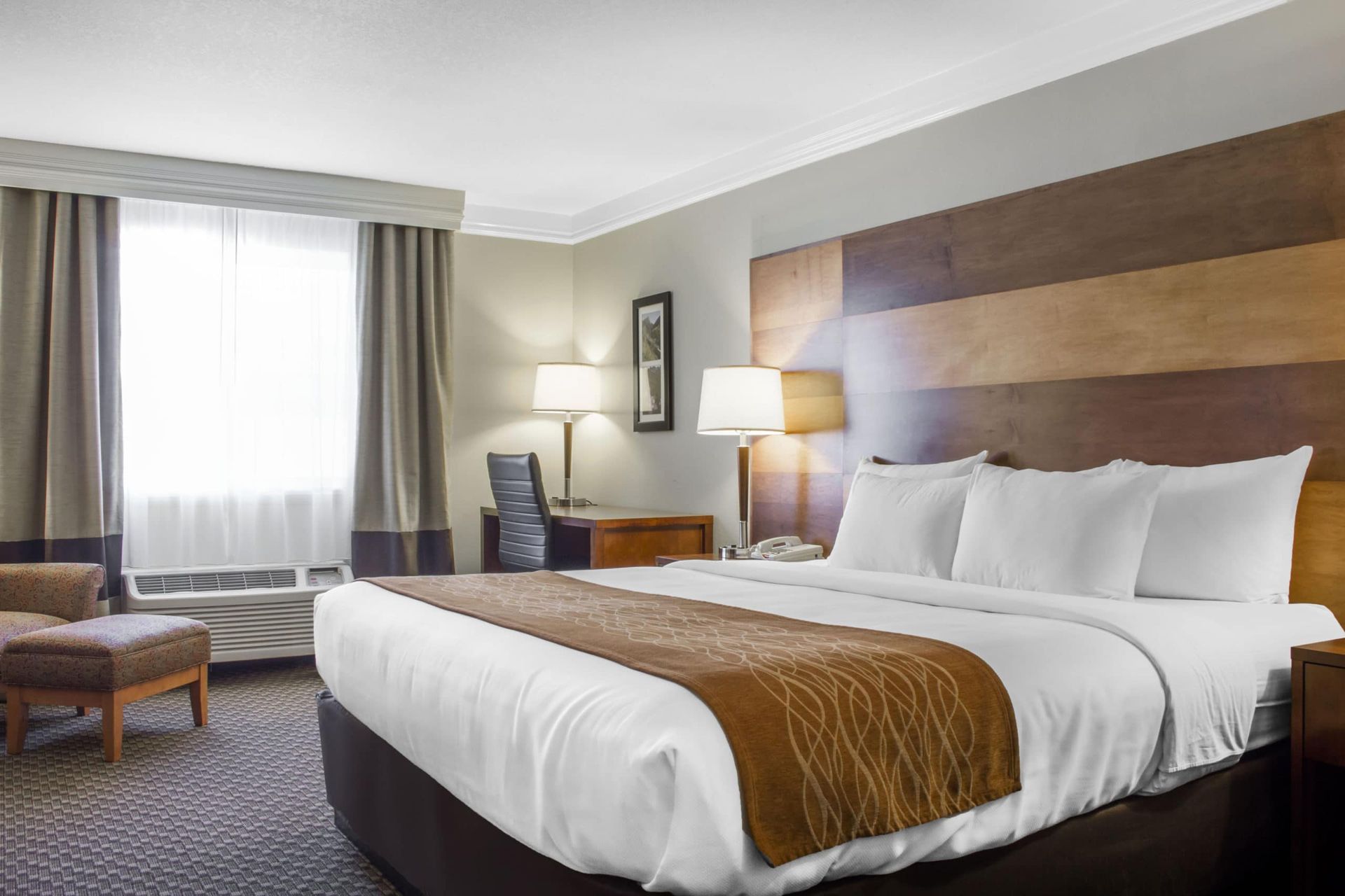 A hotel room with a king size bed and a chair.