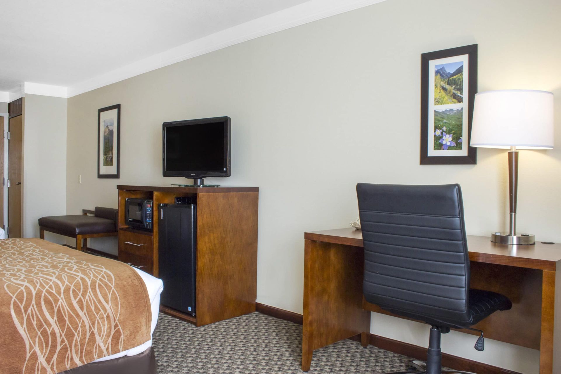 A hotel room with a bed , desk and television