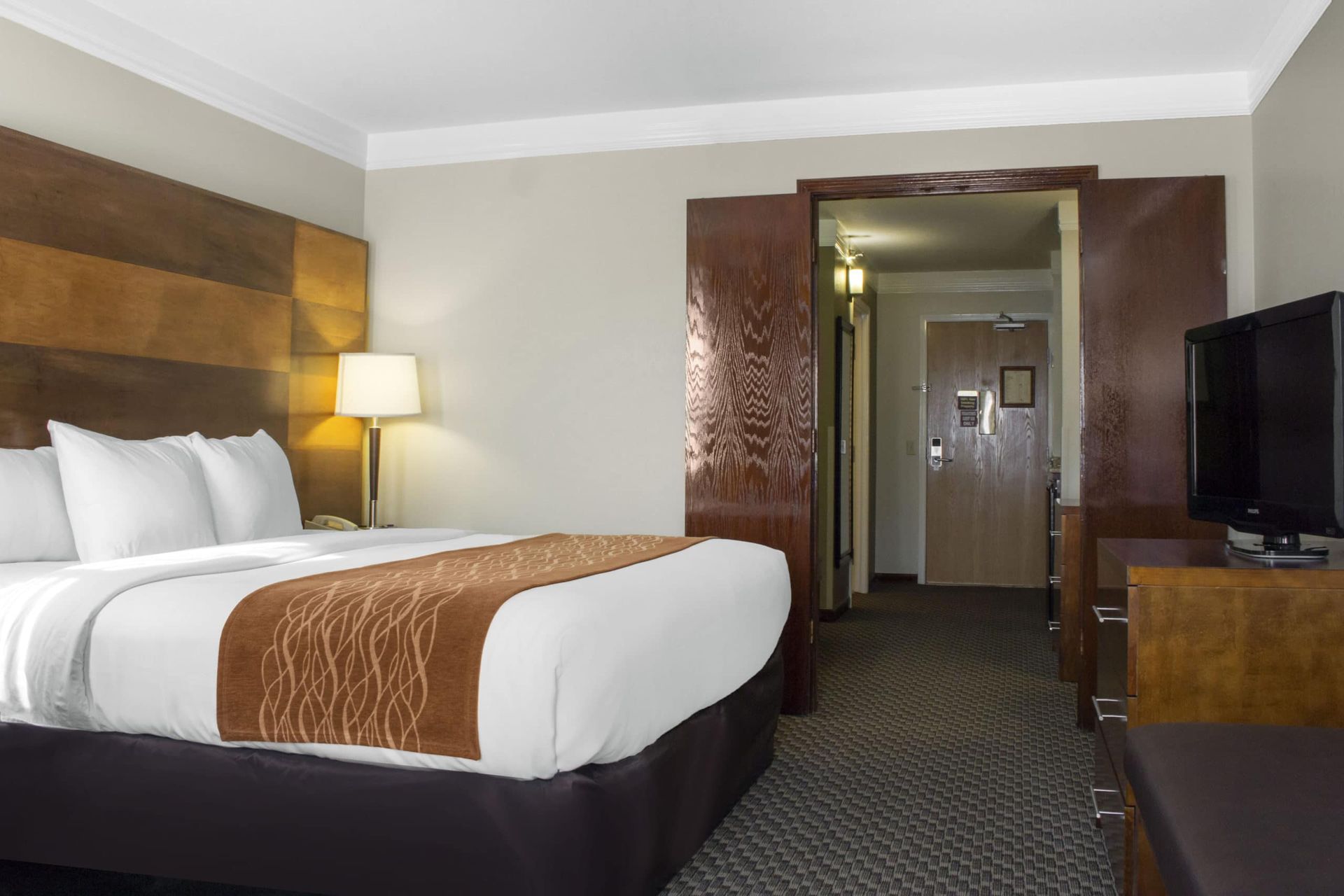 A hotel room with a king size bed and a flat screen tv.