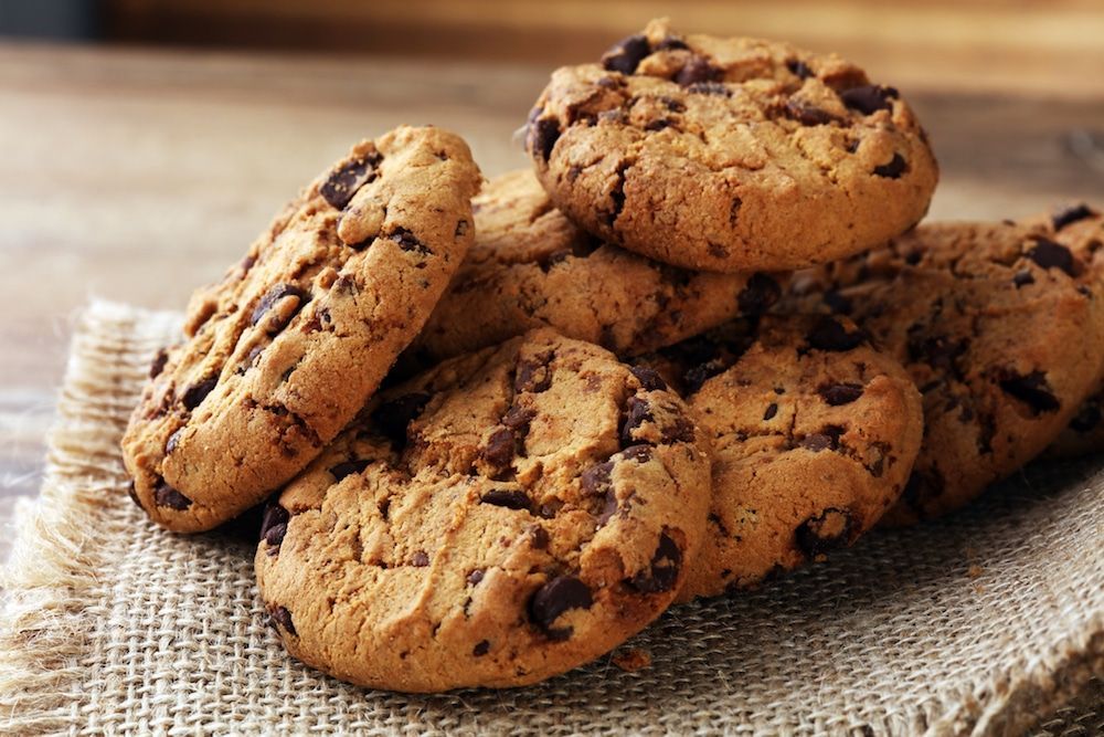 A pile of chocolate chip cookies stacked on top of each other on a table.