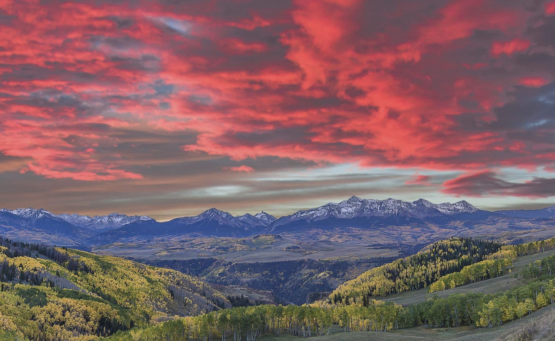 A sunset over a mountain range with red clouds in the sky