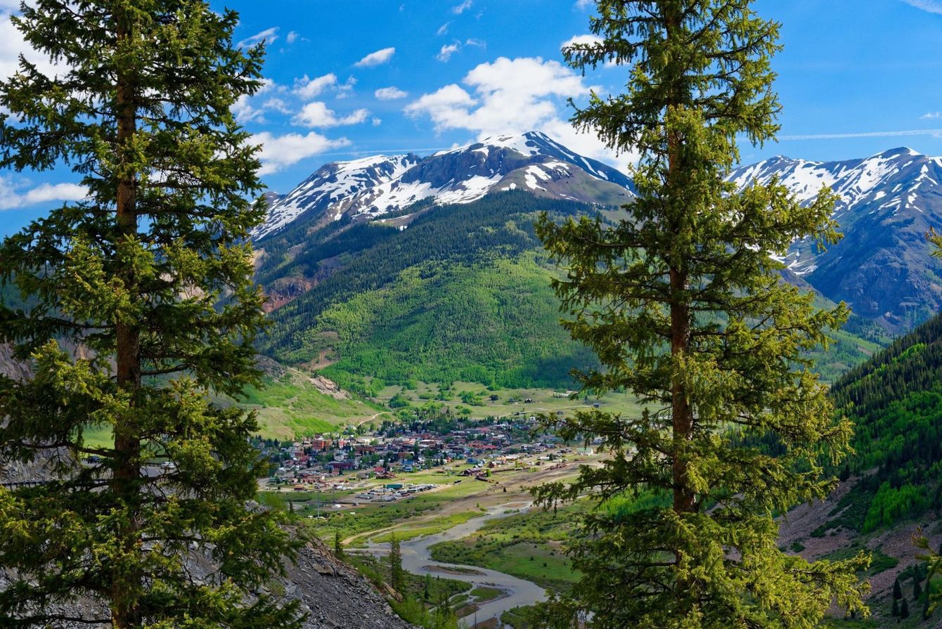 A view of a valley with mountains in the background and trees in the foreground.