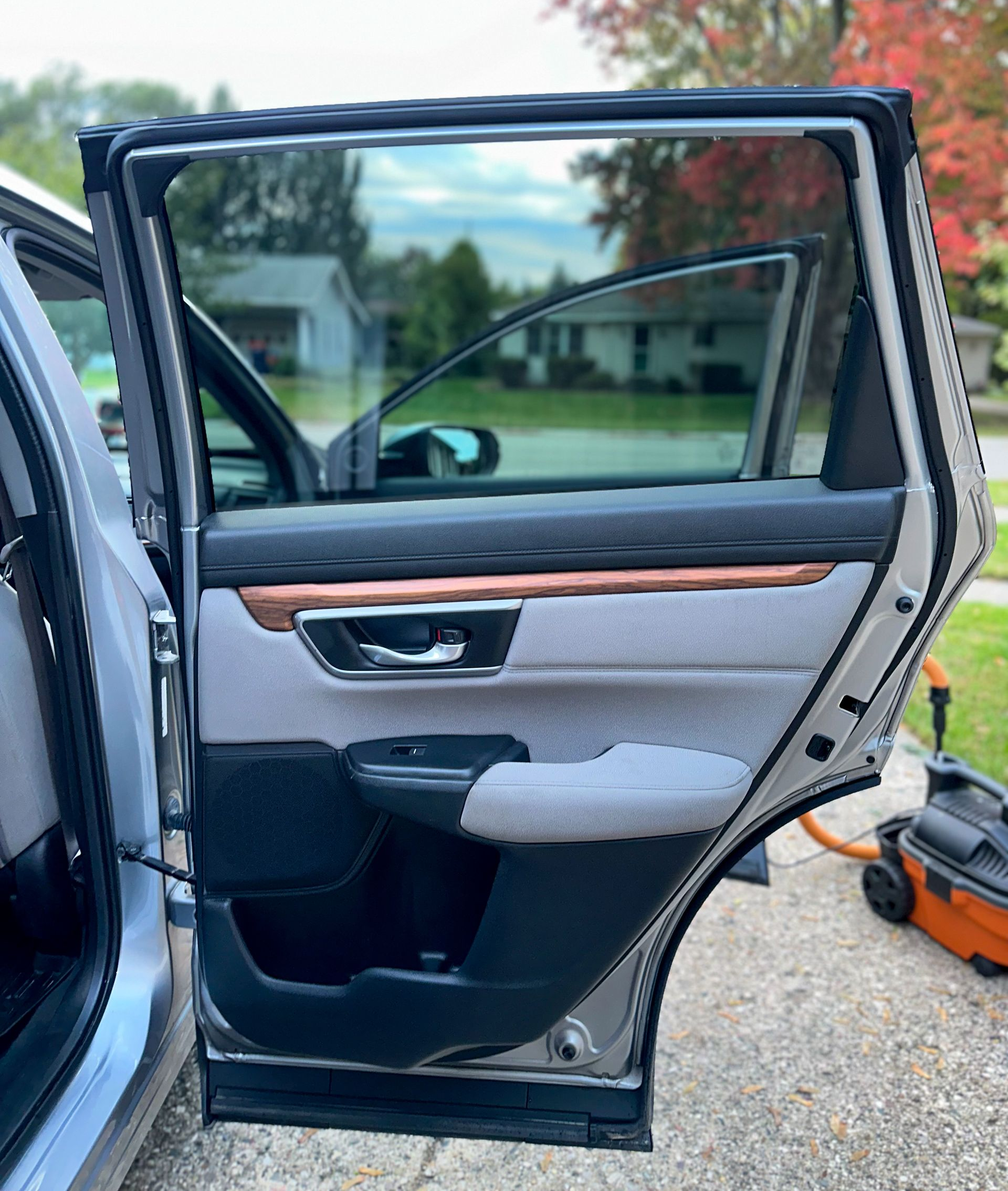 Open car door, gray interior with wood trim, outside in front of house.