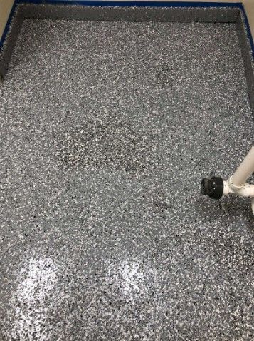 Gray speckled floor with a small white pipe or nozzle at the lower right edge.