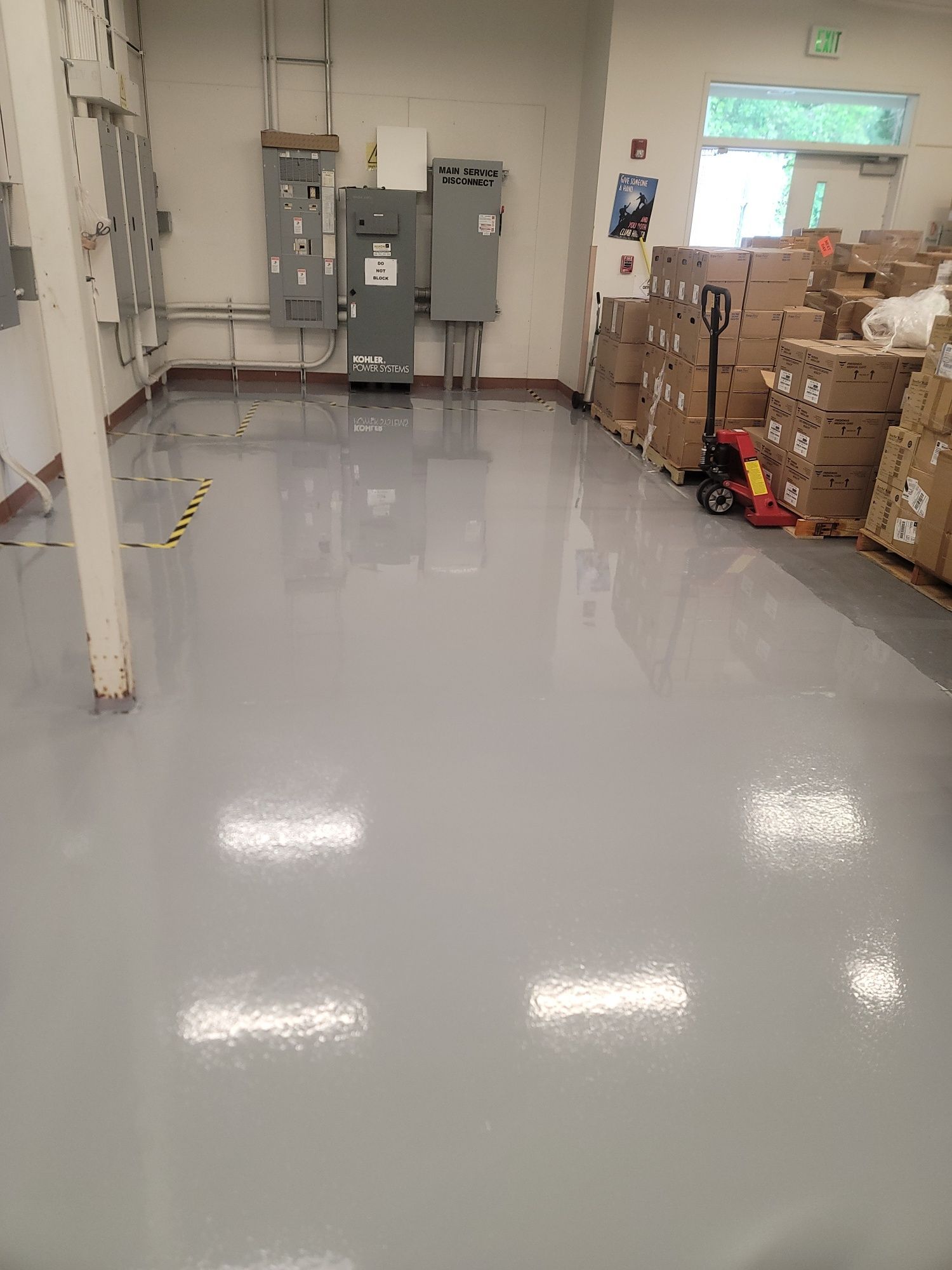 Utility room with a large central duct, pipes along the walls, and a gray concrete floor.