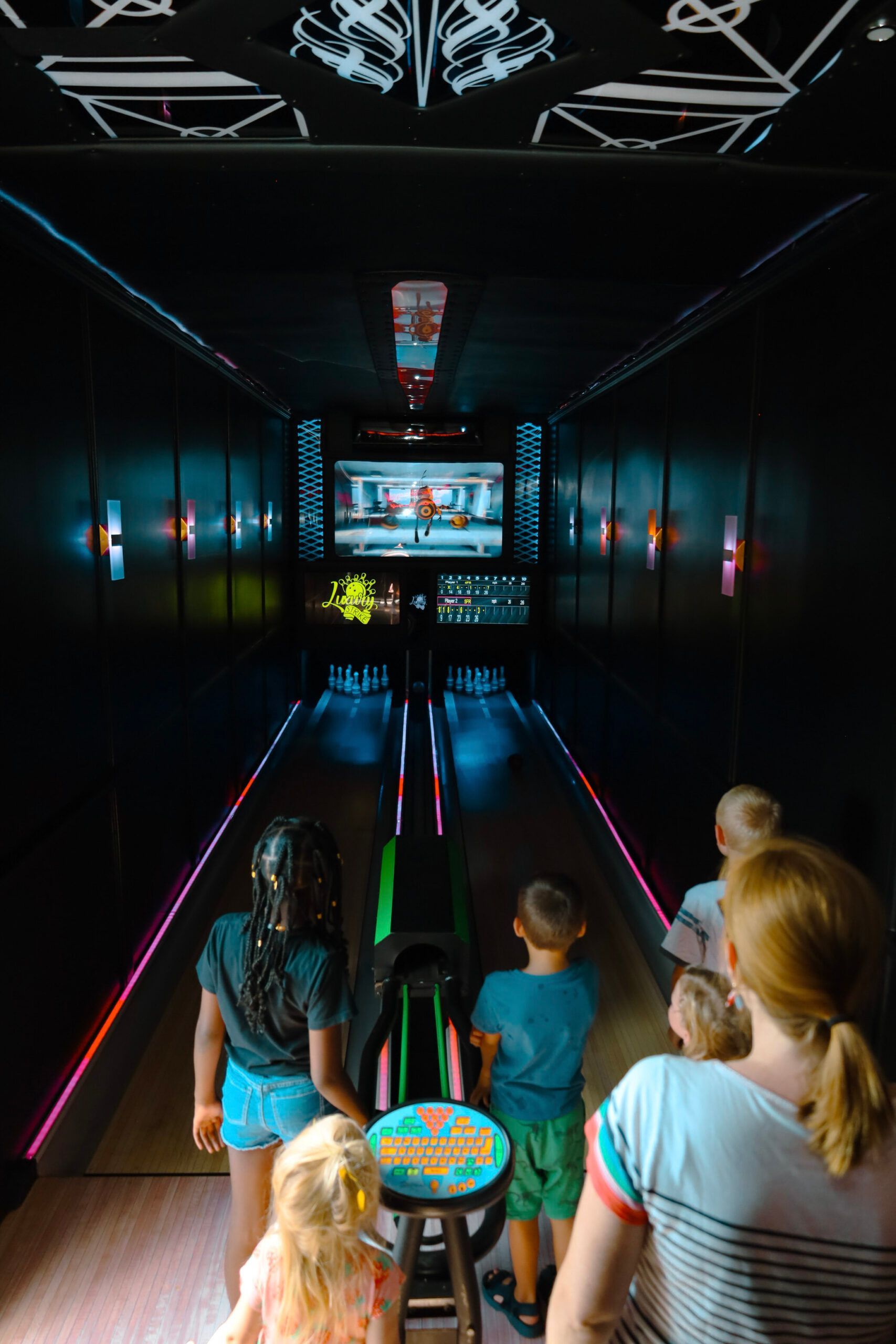 A group of people are playing bowling in a dark room.