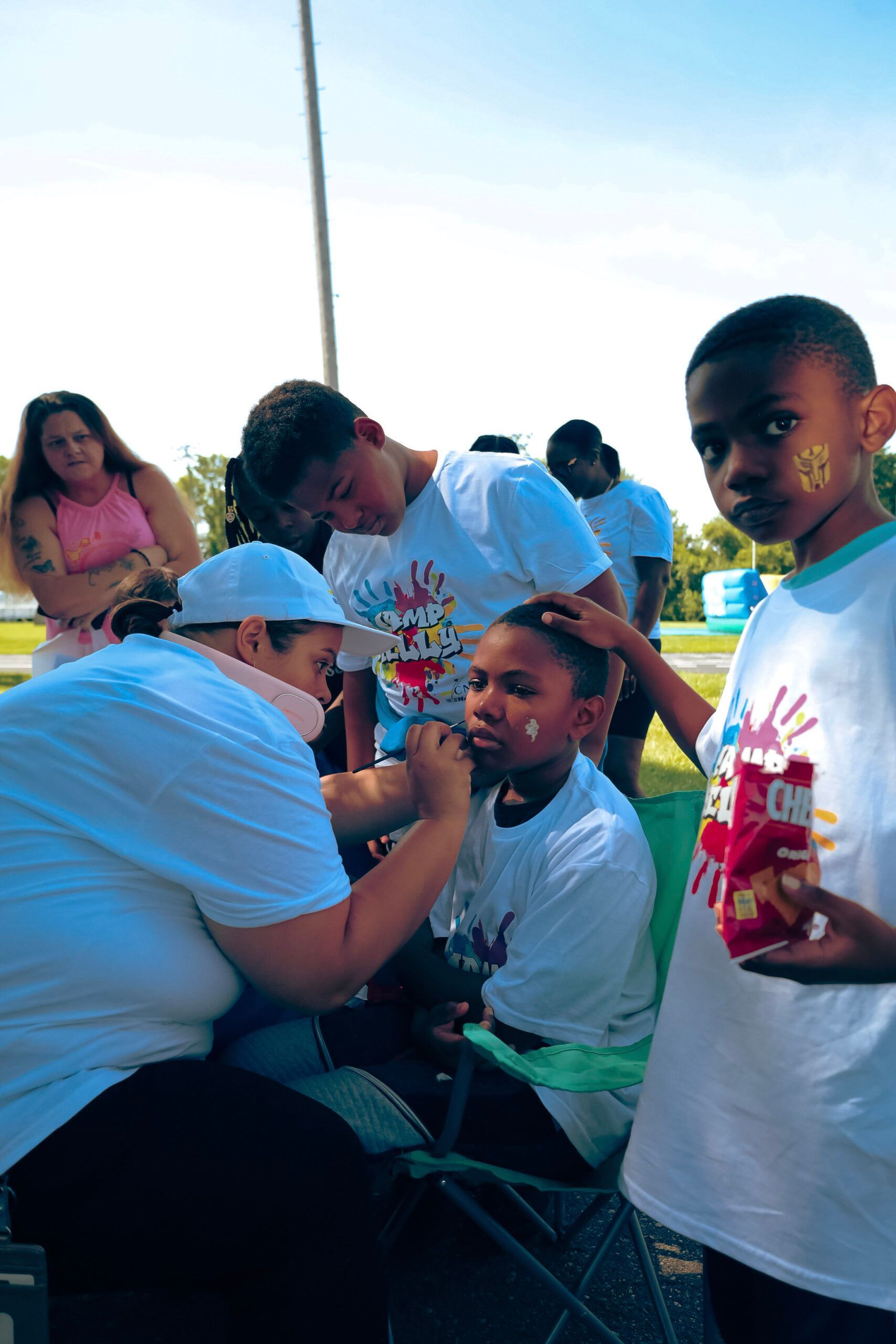 A group of children are getting their faces painted by a woman