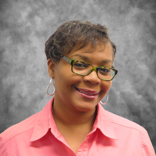 A woman wearing glasses and hoop earrings is smiling for the camera