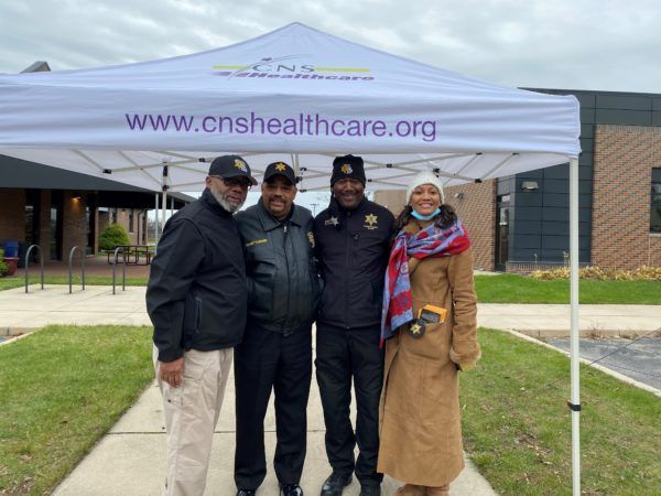 A group of people posing for a picture under a tent that says www.cnshealthcare.org