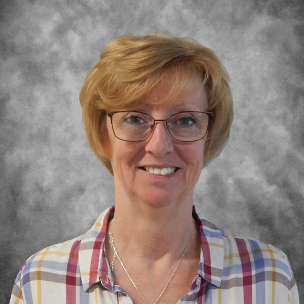 A woman wearing glasses and a plaid shirt smiles for the camera