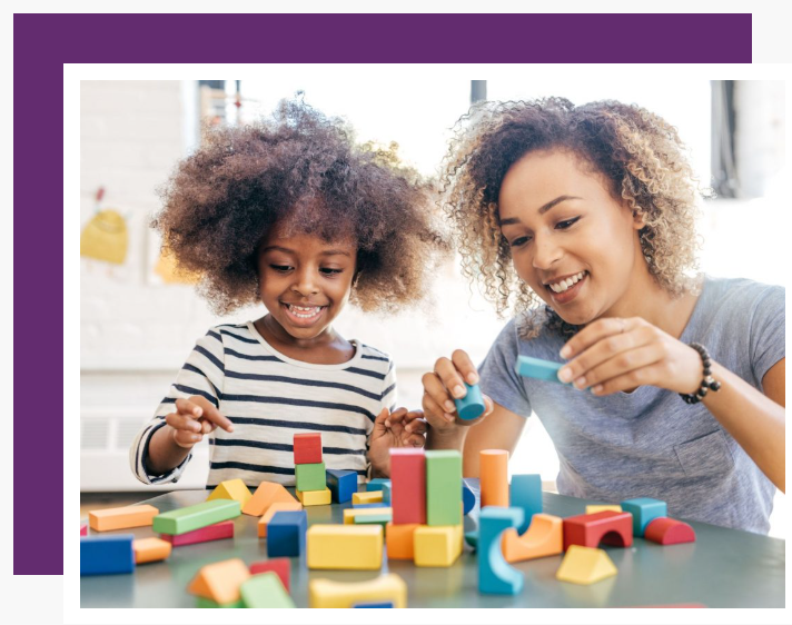 A woman and a child are playing with wooden blocks at a table.