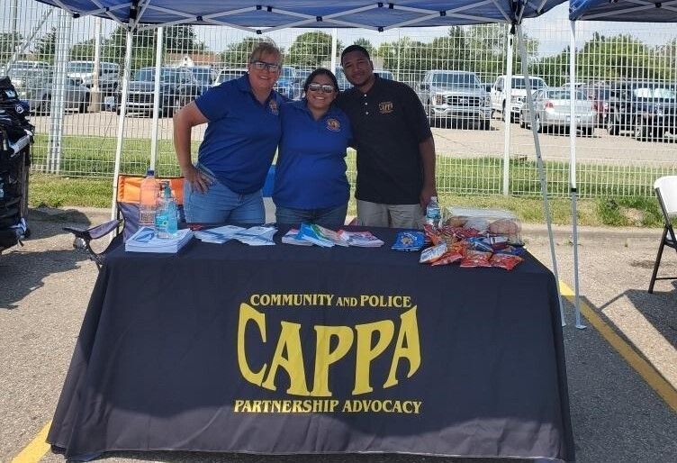 A group of people standing around a table that says cappa