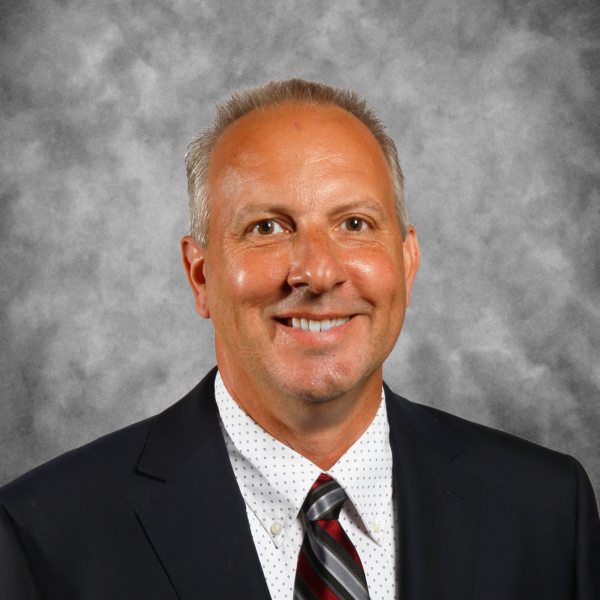 A man in a suit and tie is smiling for the camera