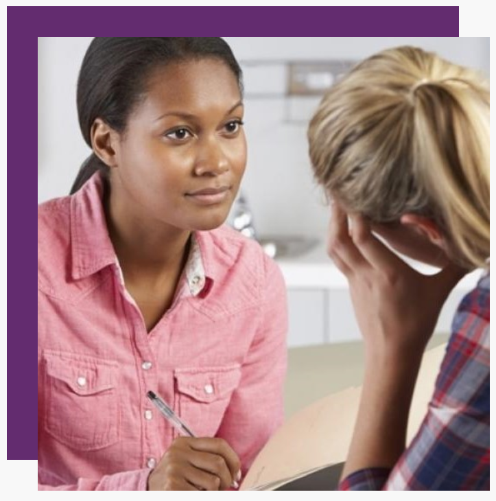 A woman in a pink shirt is talking to another woman