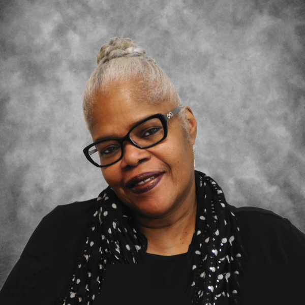 A woman wearing glasses and a scarf smiles for the camera