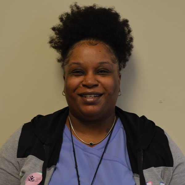 A woman wearing glasses and a floral scarf smiles for the camera