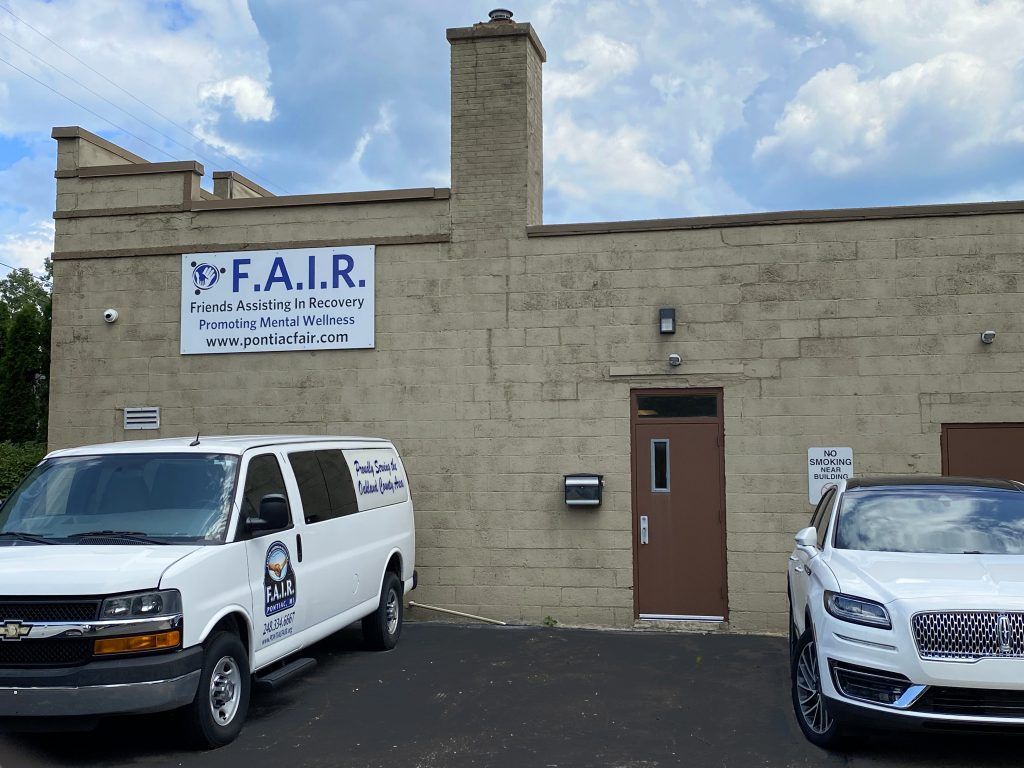 Two white vans are parked in front of a building that says f.a.i.r.