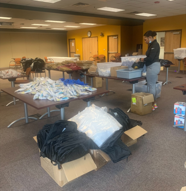 A man is standing in a room filled with tables and boxes