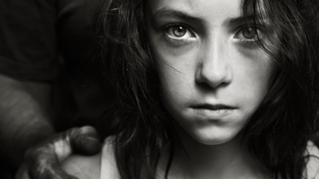 A black and white photo of a young girl looking at the camera.