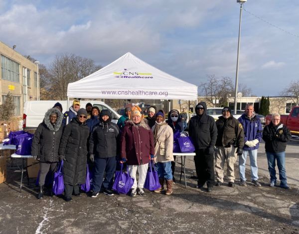 A group of people are standing under a tent in a parking lot.