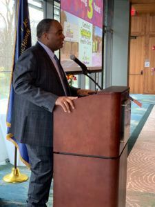 A man in a suit is standing at a podium giving a speech.