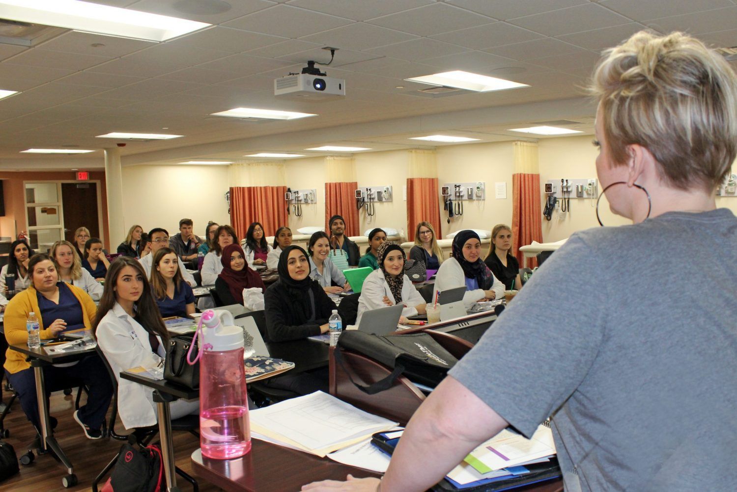 A woman is giving a presentation to a group of people in a classroom.