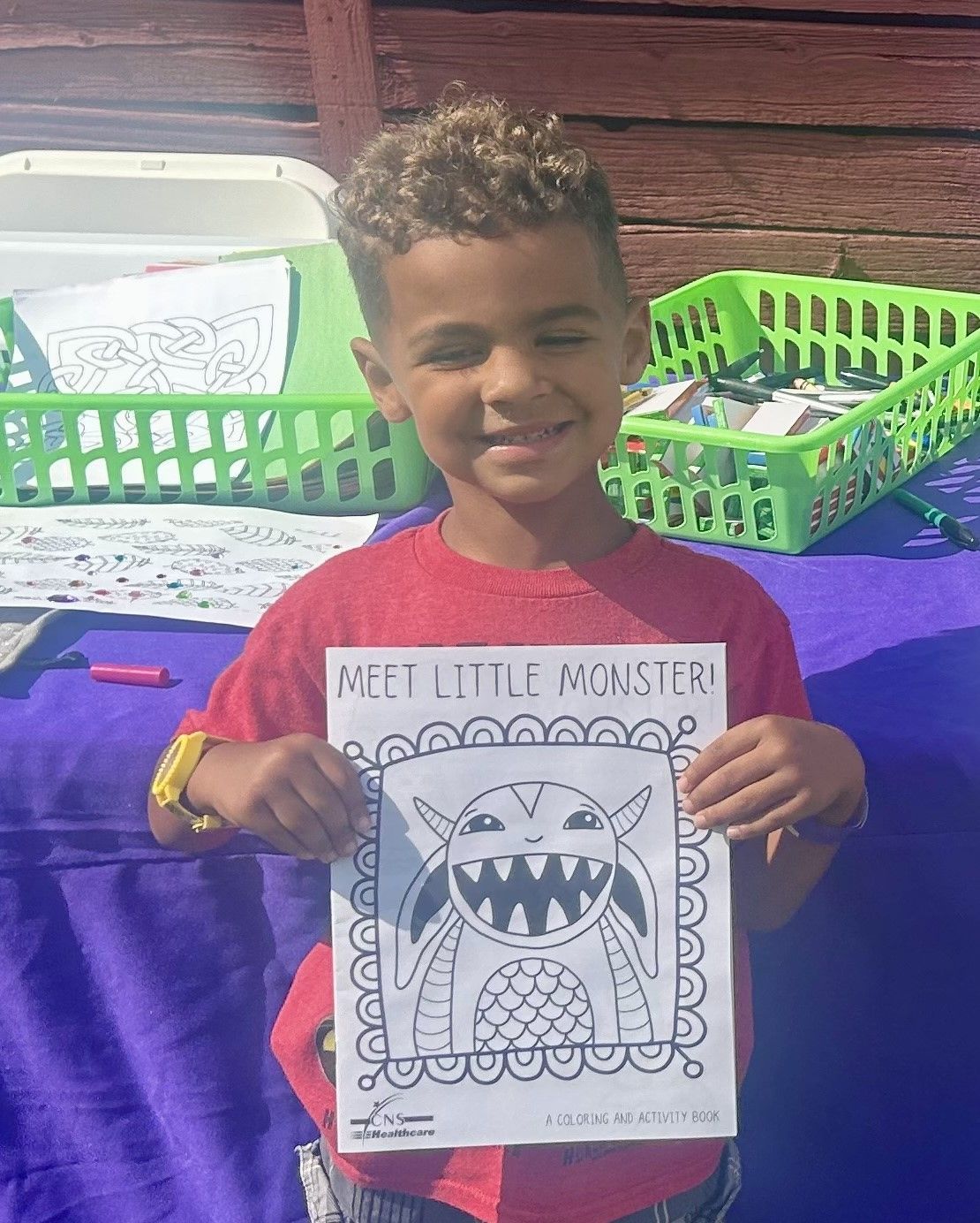 A young boy in a red shirt is holding a drawing of a monster.