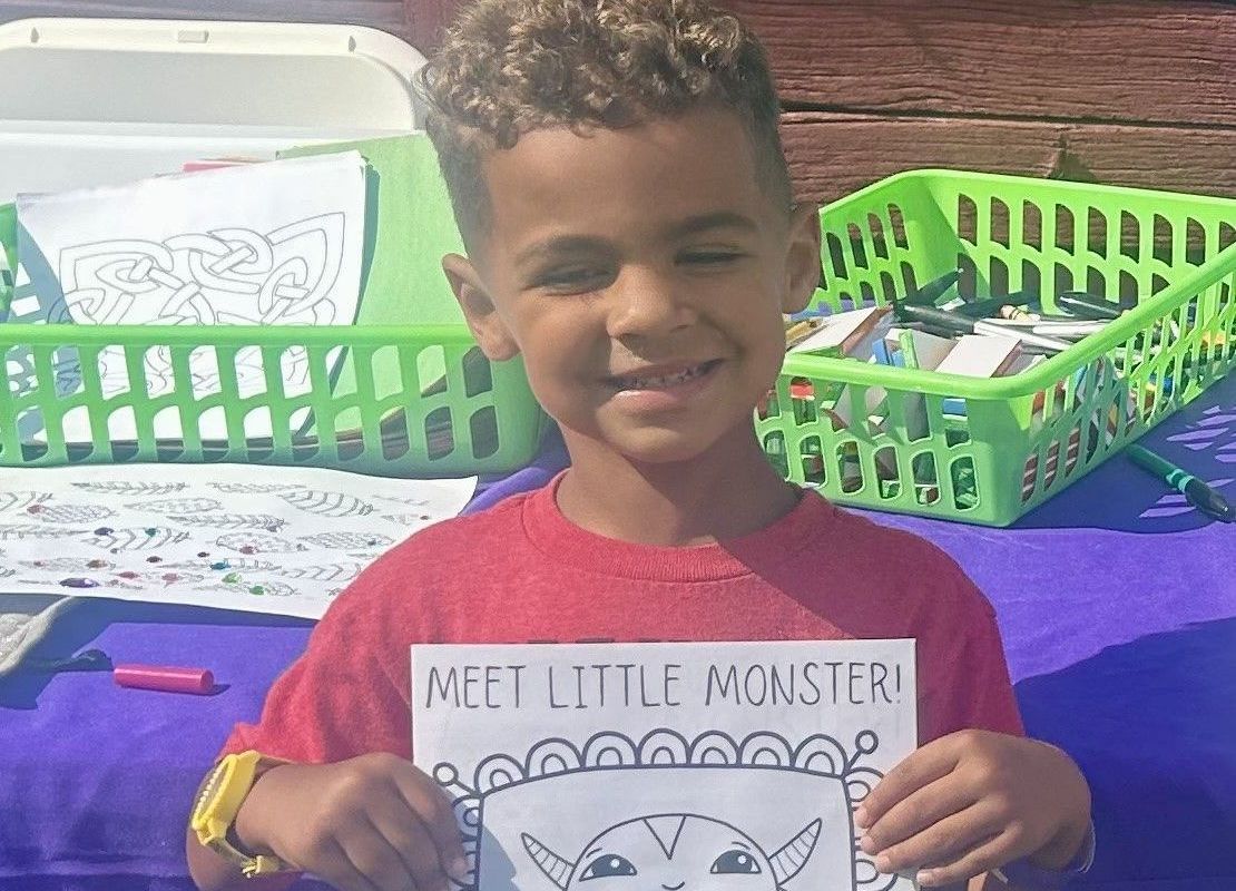 A young boy is holding a sign that says meet little monster.