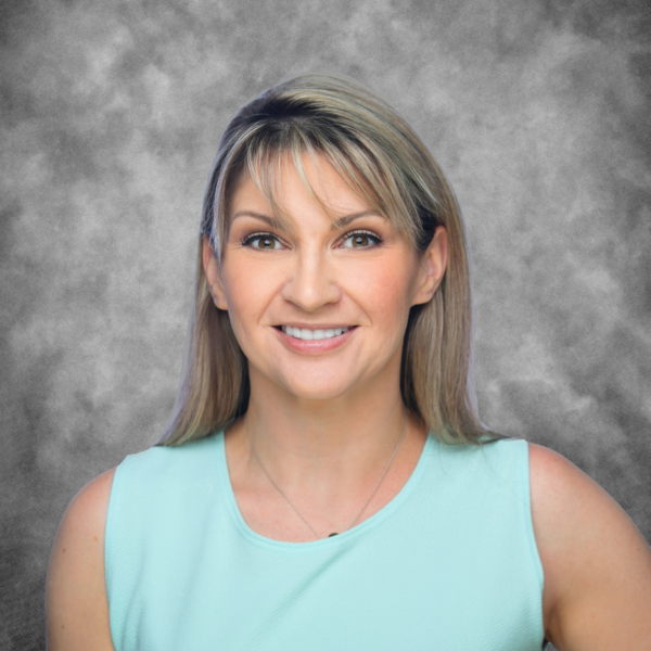 A woman in a light blue shirt is smiling for the camera.