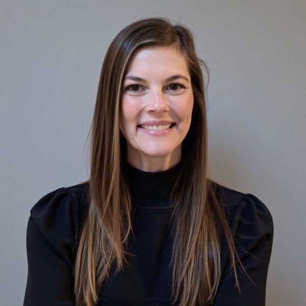 A woman with long hair is smiling and wearing a black sweater.