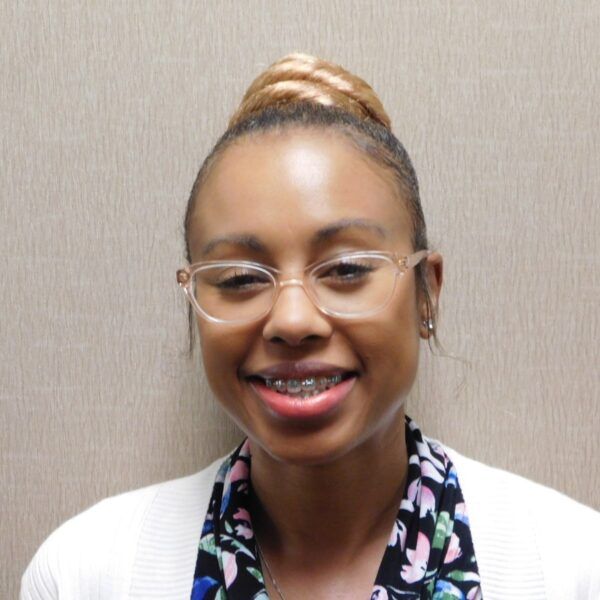 A woman wearing glasses and a floral scarf smiles for the camera