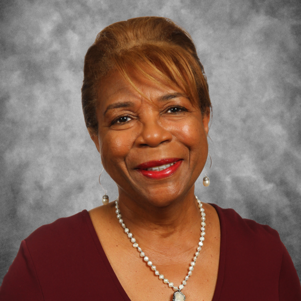 A woman wearing a necklace and earrings smiles for the camera