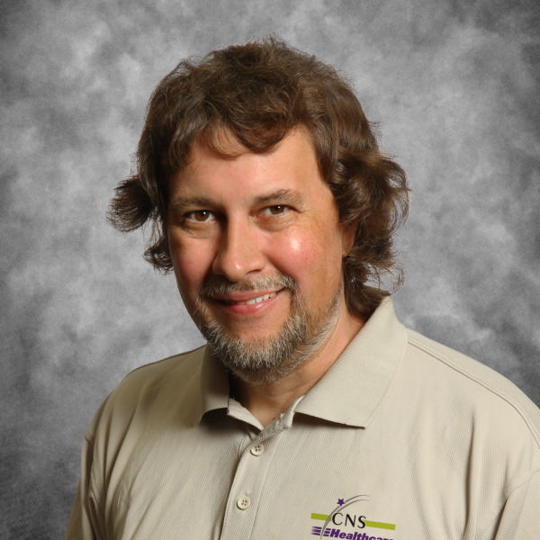 A man wearing a cns healthcare shirt smiles for the camera