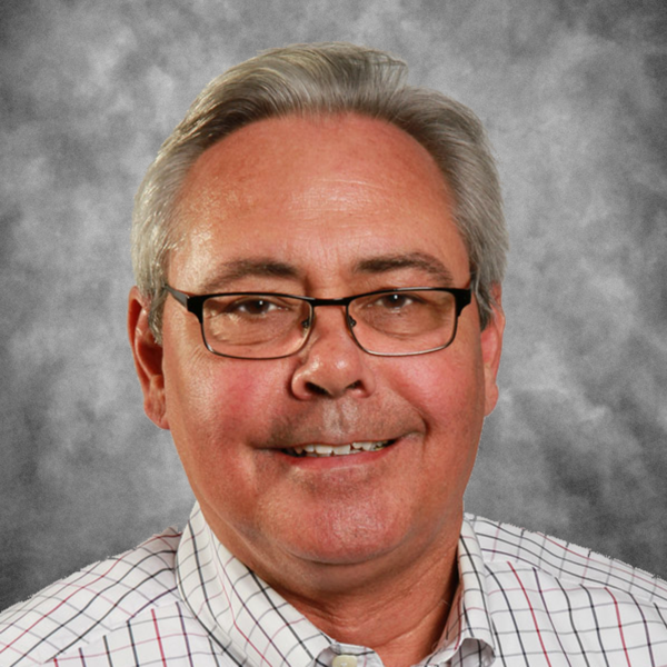 A man wearing glasses and a plaid shirt smiles for the camera