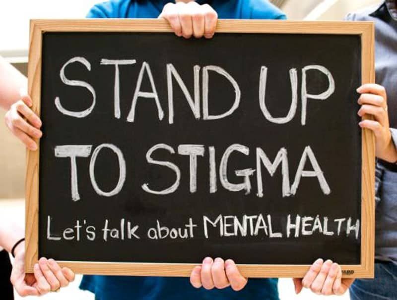 People holding a sign that says stand up to stigma let 's talk about mental health