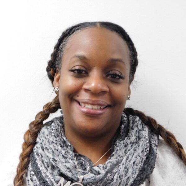 A woman wearing glasses and a scarf is smiling for the camera.