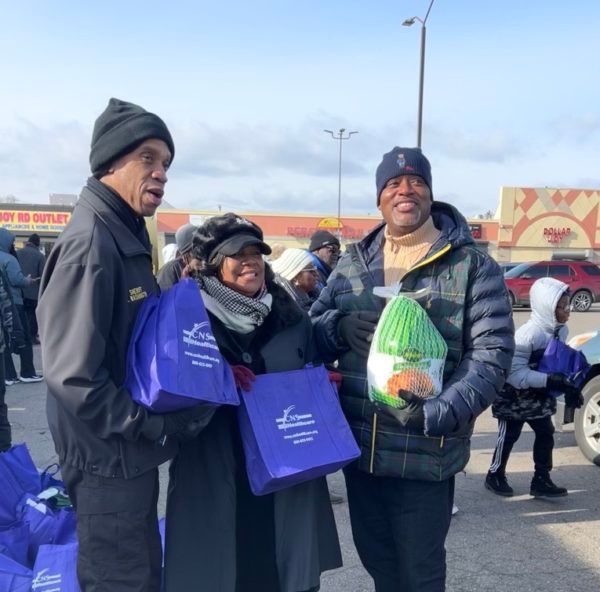 A group of people are standing in front of a store holding purple bags