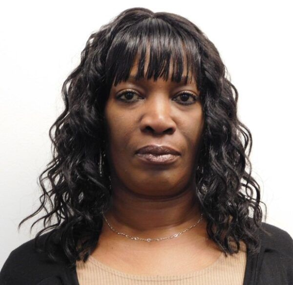 Woman with dark skin wearing braids, hoop earrings, nose ring, and a pendant smiling.