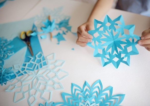 A child is making paper snowflakes on a table.