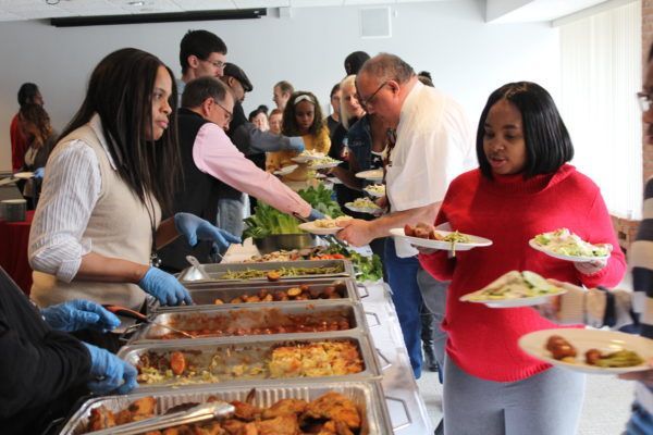 A group of people are getting food from a buffet line