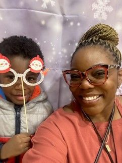 A woman and a child wearing santa claus glasses on sticks.