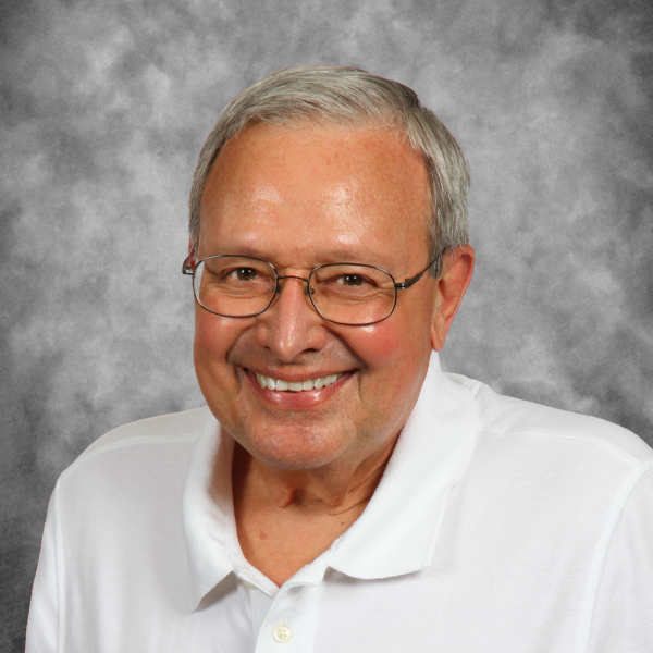 A man wearing glasses and a white shirt smiles for the camera