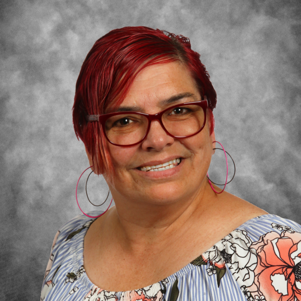 A woman with red hair and glasses is smiling for the camera