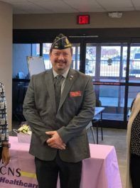 A man in a suit and hat is standing in front of a table.