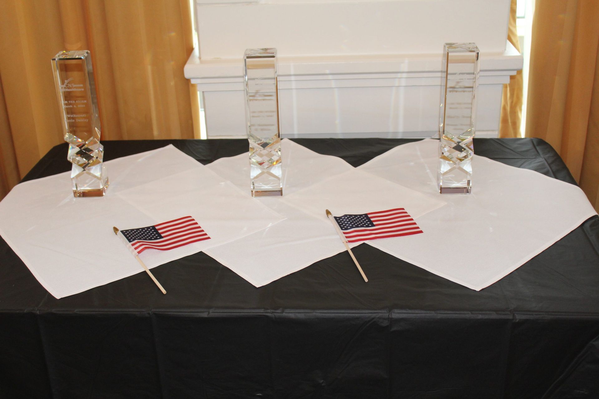 Three trophies and two american flags on a table