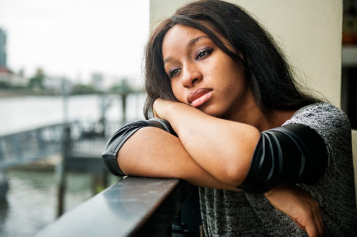 A woman is leaning on a railing looking out a window.