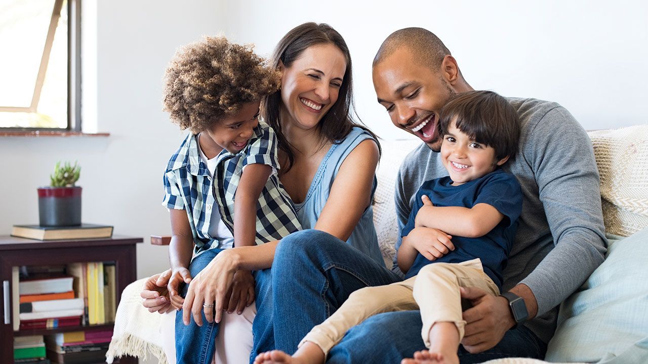 A family is sitting on a couch together and smiling.