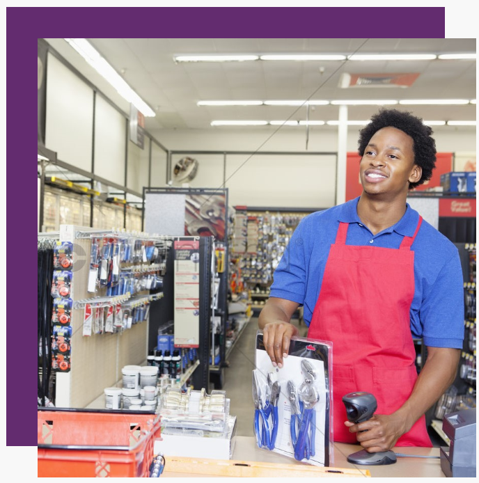 A man in a red apron is using a scanner in a store